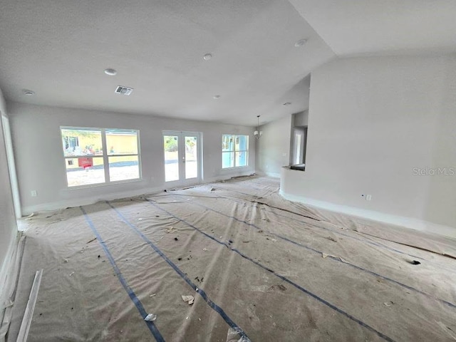 unfurnished living room with lofted ceiling, french doors, and visible vents