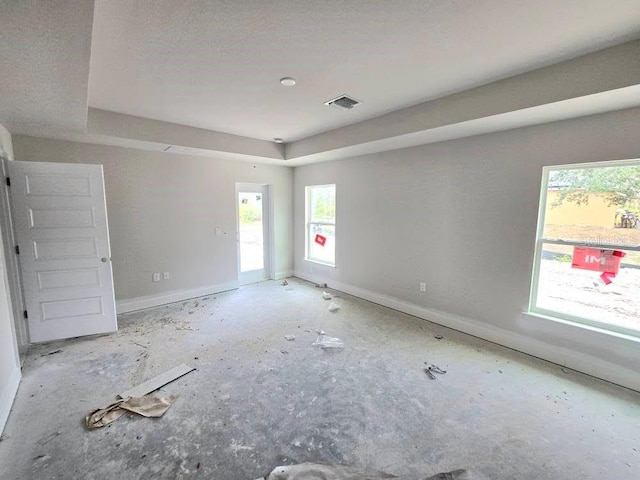 spare room featuring baseboards, visible vents, and a raised ceiling