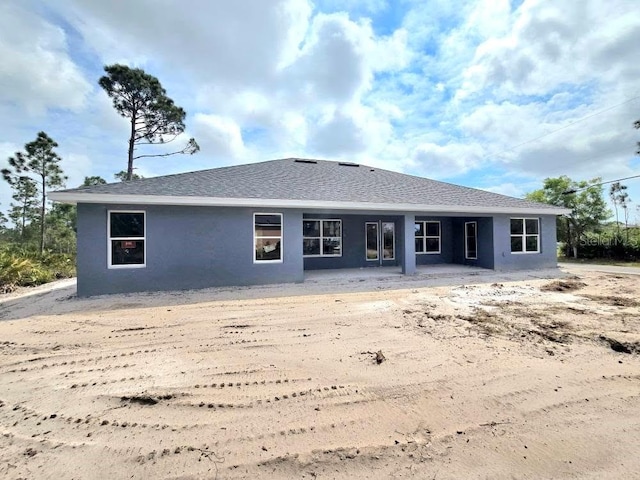 rear view of property with roof with shingles and stucco siding