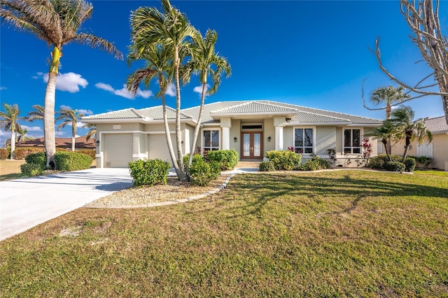 view of front of house with an attached garage, driveway, french doors, stucco siding, and a front yard