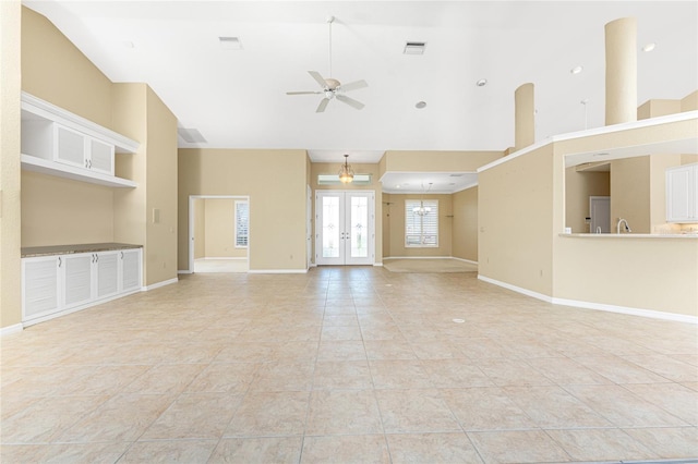 unfurnished living room with ceiling fan, french doors, a towering ceiling, and light tile patterned flooring