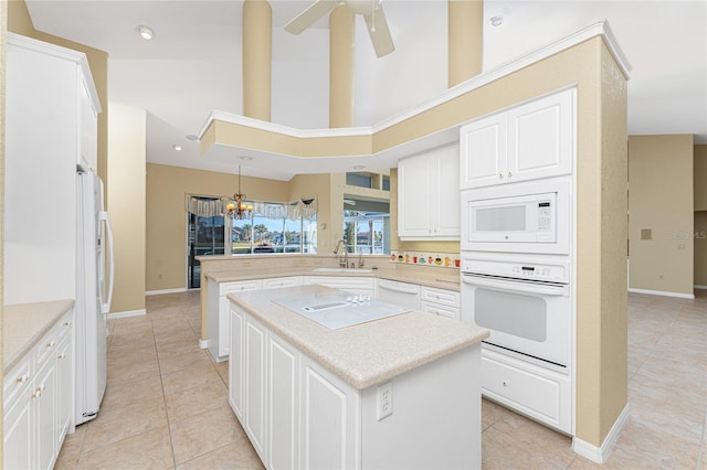 kitchen with a center island, kitchen peninsula, sink, a high ceiling, and white appliances