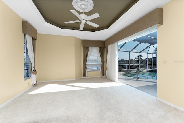 carpeted empty room with ceiling fan and a tray ceiling