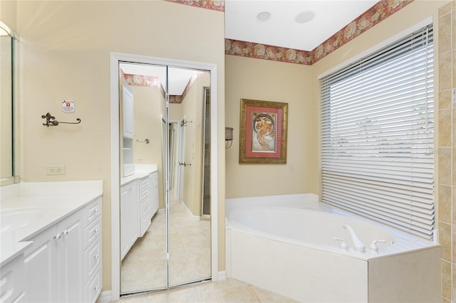 bathroom with tile patterned flooring, a tub to relax in, and vanity