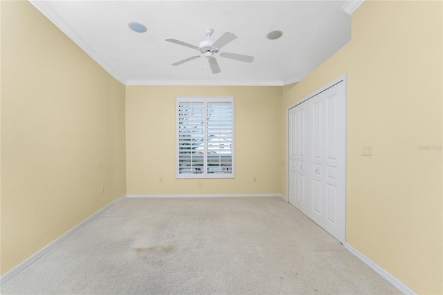 unfurnished bedroom with ceiling fan, crown molding, light colored carpet, and a closet