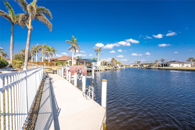 dock area with a water view, fence, and a residential view