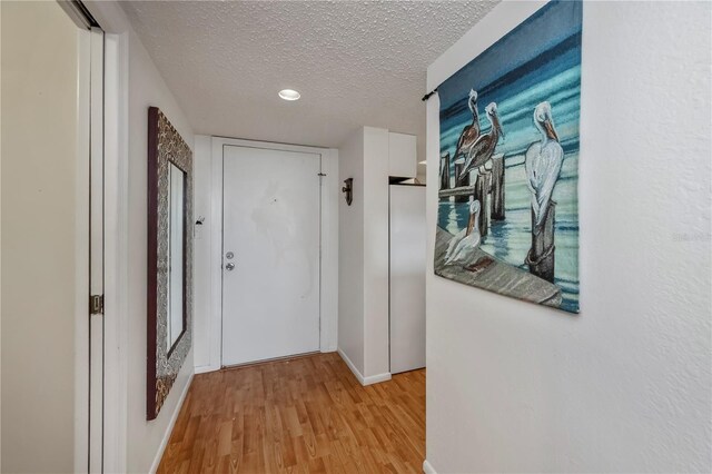 corridor featuring a textured ceiling and light hardwood / wood-style flooring