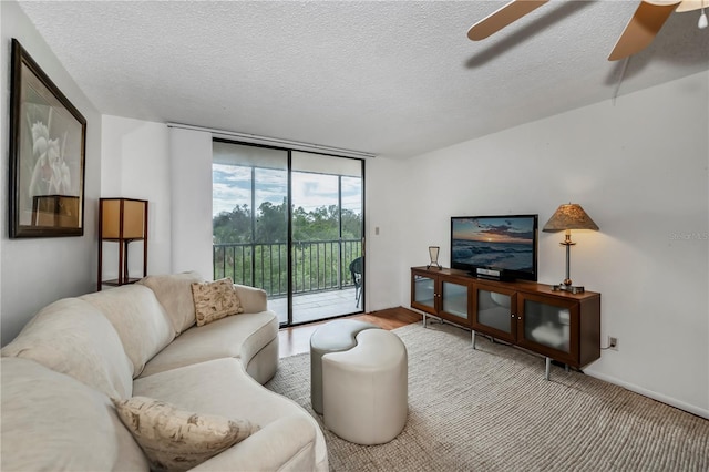 living room featuring ceiling fan, a textured ceiling, a wall of windows, and hardwood / wood-style floors