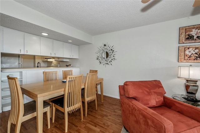 dining area with wood-type flooring, sink, and a textured ceiling