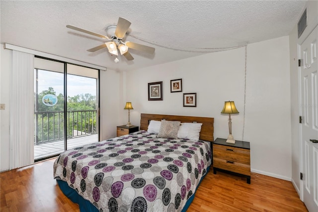 bedroom with ceiling fan, light hardwood / wood-style floors, access to outside, a textured ceiling, and a wall of windows