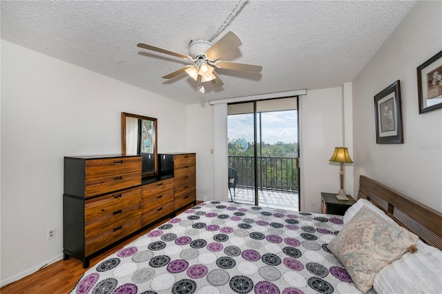 bedroom featuring hardwood / wood-style flooring, ceiling fan, access to outside, a textured ceiling, and expansive windows