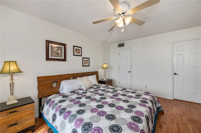 bedroom with ceiling fan, a textured ceiling, and hardwood / wood-style floors