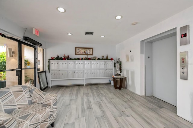 interior space featuring light hardwood / wood-style floors, a mail area, and elevator