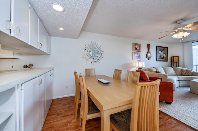 dining room featuring light hardwood / wood-style floors, a textured ceiling, and ceiling fan