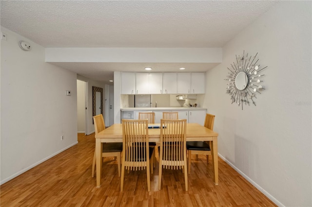 dining room featuring light wood-type flooring and a textured ceiling