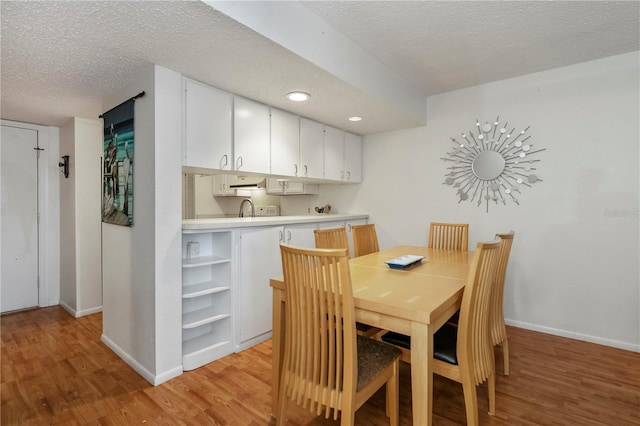 dining room with a textured ceiling, light hardwood / wood-style flooring, and sink