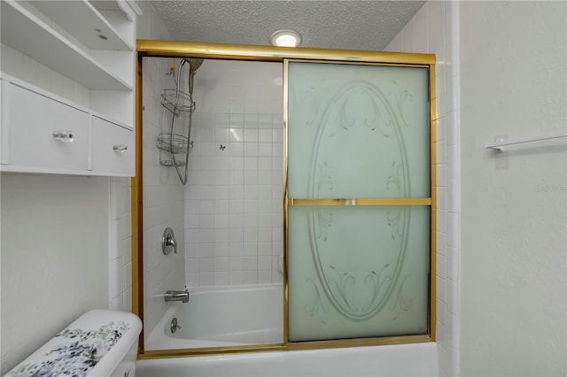 bathroom with a textured ceiling, toilet, and shower / bath combination with glass door