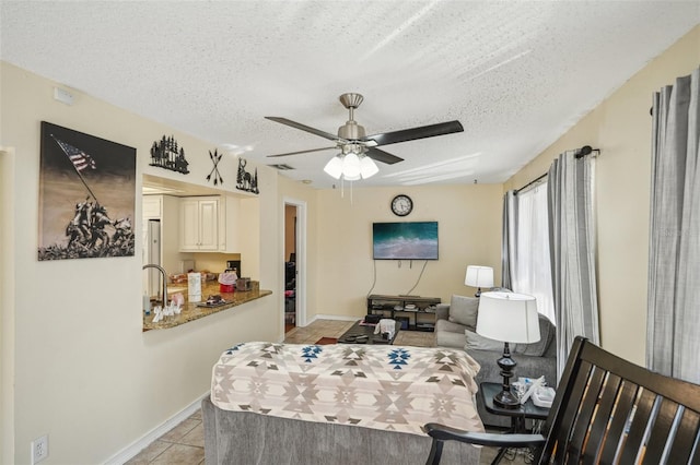 tiled living room featuring a textured ceiling, ceiling fan, and sink