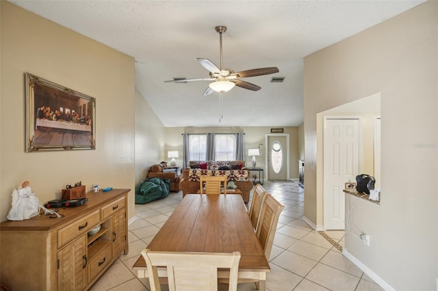 tiled dining room with ceiling fan, vaulted ceiling, and a textured ceiling