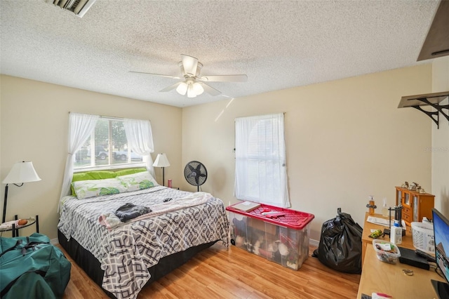 bedroom with hardwood / wood-style floors, a textured ceiling, and ceiling fan