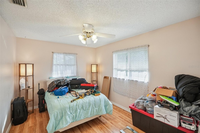 bedroom featuring a textured ceiling, ceiling fan, and light hardwood / wood-style floors