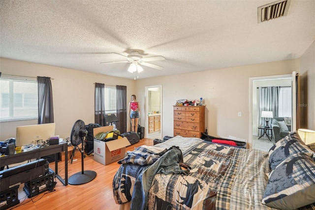 bedroom featuring connected bathroom, a textured ceiling, ceiling fan, and light hardwood / wood-style floors