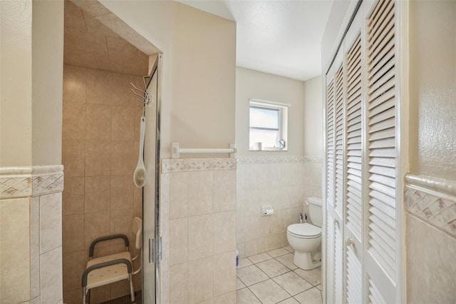 bathroom with tile walls, toilet, tile patterned floors, and walk in shower