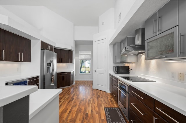 kitchen featuring dark wood-type flooring, wall chimney range hood, and black appliances