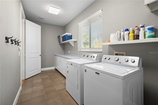 clothes washing area featuring cabinets, tile patterned floors, and washer and clothes dryer