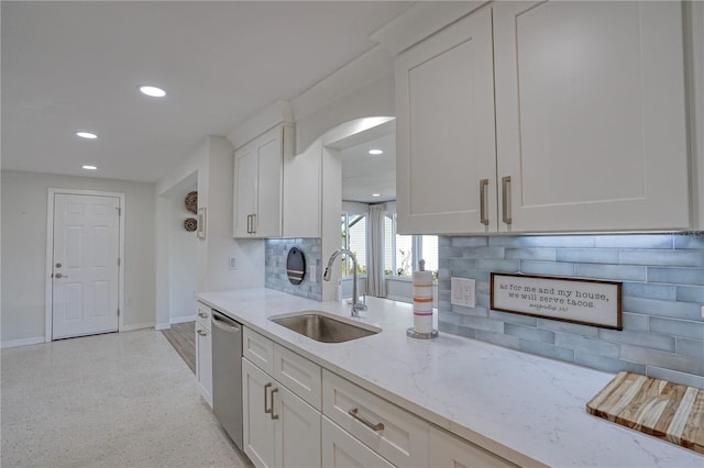 kitchen featuring backsplash, light stone countertops, stainless steel dishwasher, white cabinets, and sink