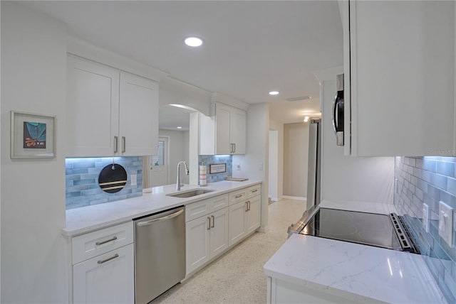 kitchen featuring white cabinetry, appliances with stainless steel finishes, backsplash, light stone countertops, and sink