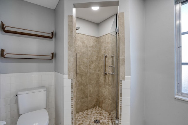 bathroom featuring toilet, tile walls, and a shower with door