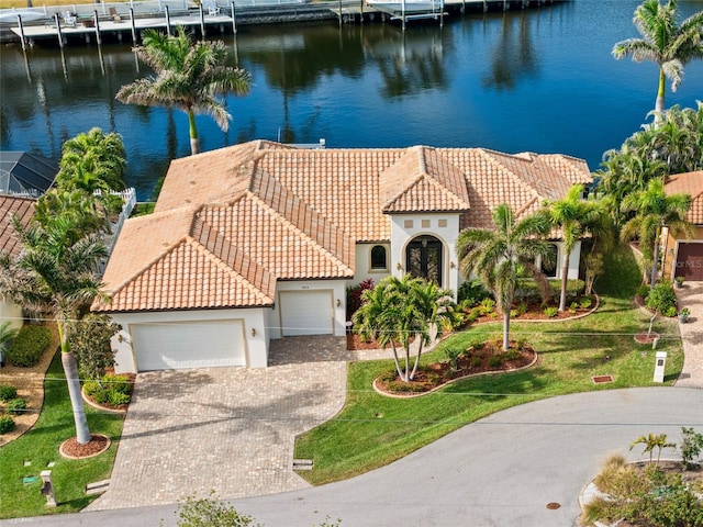 mediterranean / spanish house with a garage, a front yard, and a water view