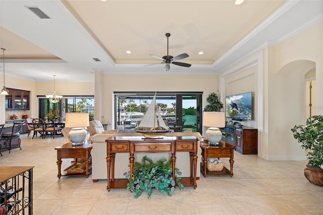 tiled living room with ceiling fan with notable chandelier, crown molding, and a tray ceiling