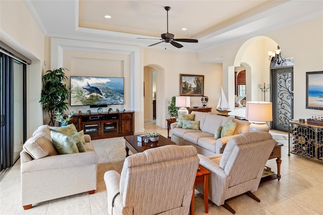 living room featuring crown molding, ceiling fan with notable chandelier, and a tray ceiling