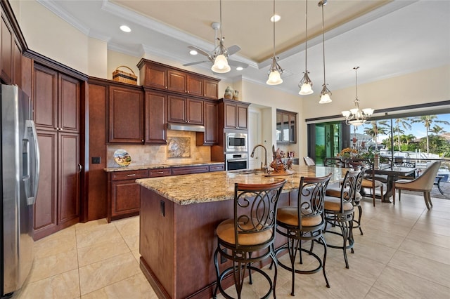 kitchen with pendant lighting, a tray ceiling, stainless steel appliances, and a spacious island