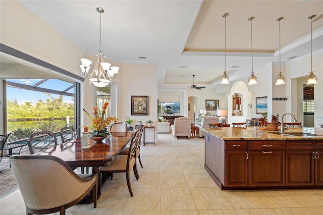 kitchen featuring crown molding, pendant lighting, sink, light stone countertops, and a tray ceiling