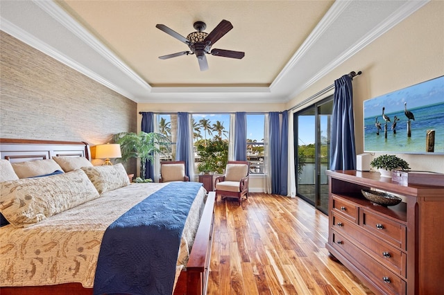 bedroom featuring crown molding, ceiling fan, a tray ceiling, access to exterior, and light hardwood / wood-style floors