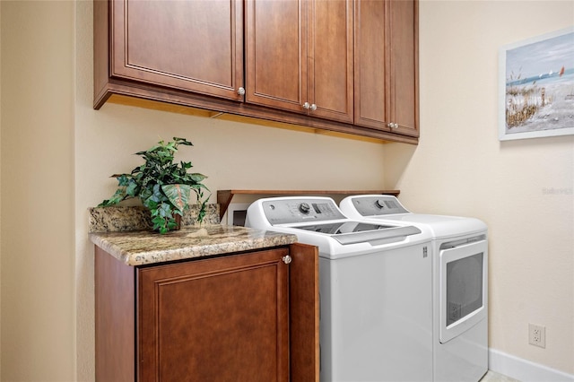 clothes washing area featuring cabinets and washer and clothes dryer