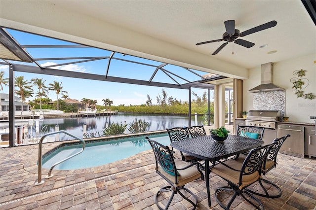 view of pool featuring a patio area, a water view, area for grilling, a lanai, and exterior kitchen