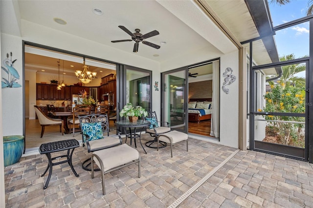 sunroom featuring ceiling fan with notable chandelier and plenty of natural light