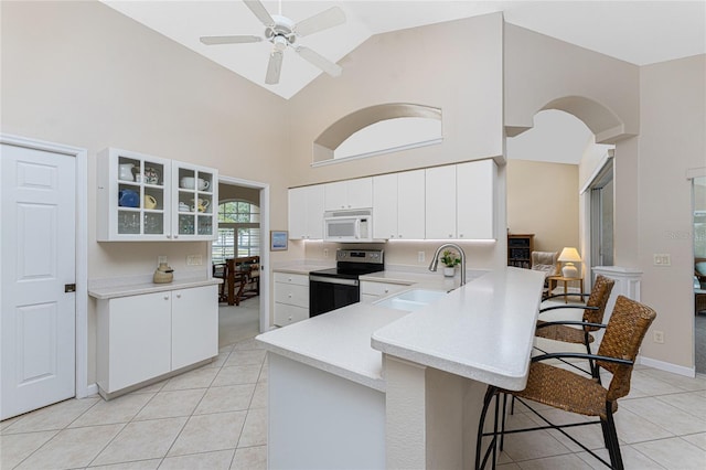 kitchen featuring sink, electric range, white cabinets, and a kitchen breakfast bar