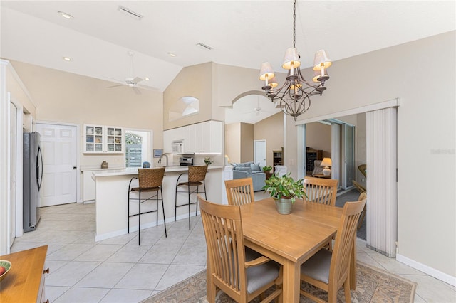 dining room featuring ceiling fan with notable chandelier, high vaulted ceiling, and light tile patterned flooring