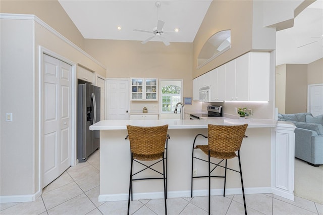 kitchen featuring kitchen peninsula, a kitchen bar, white cabinetry, and stainless steel appliances