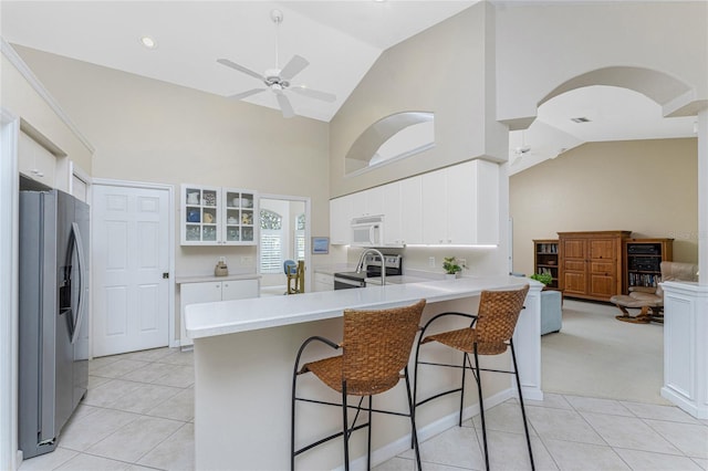 kitchen with white cabinets, appliances with stainless steel finishes, kitchen peninsula, ceiling fan, and a breakfast bar