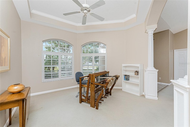 carpeted dining area featuring decorative columns, a tray ceiling, ornamental molding, and ceiling fan