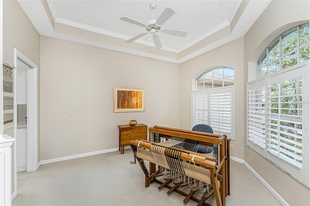 carpeted office space with crown molding, ceiling fan, and a tray ceiling