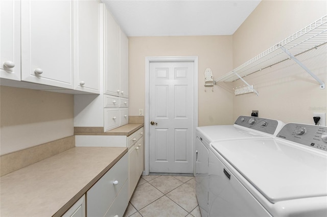 washroom featuring light tile patterned flooring, cabinets, and washer and clothes dryer