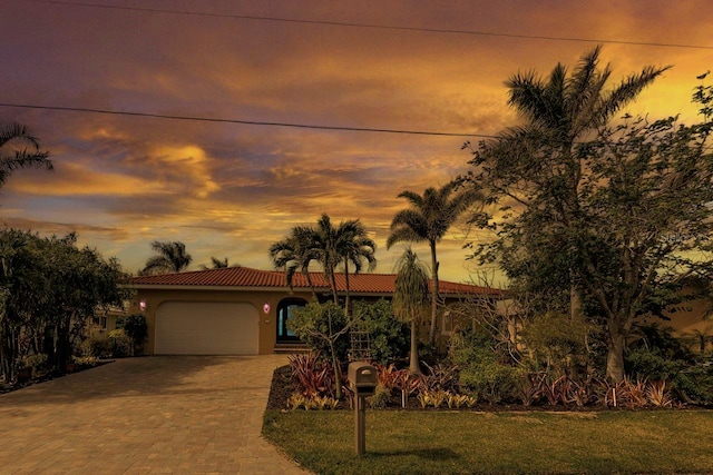 mediterranean / spanish-style home featuring a garage and a lawn