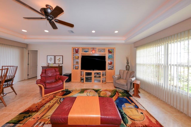 living room featuring a raised ceiling, ceiling fan, and light tile patterned flooring